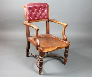 A late Victorian walnut elbow chair having part padded buttoned  back above a saddle seat, raised on ring turned tapered legs  united by a crinoline stretcher