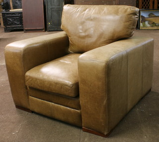 An Art Deco style brown leather open arm chair fitted loose swab cushions, raised on block feet