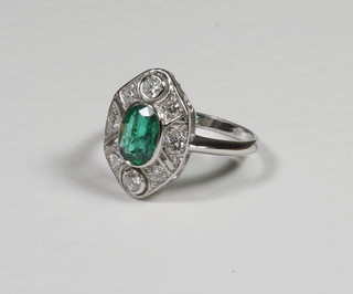 A lady's 18ct white gold dress ring set an oval cut emerald  surrounded by diamonds, approx 1/0.40ct