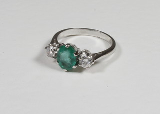 A lady's 18ct white gold dress ring set an oval cut emerald  supported by 2 diamonds approx 1.5/0.55ct