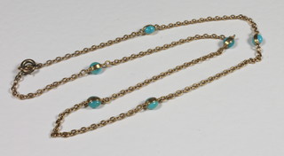 A fine gold chain interspaced with turquoise spheres