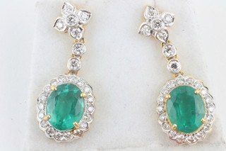 A pair of 18ct yellow gold drop earrings, set emeralds  surrounded by diamonds
