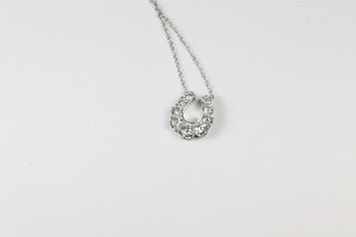 An 18ct white gold horse shoe shaped pendant set diamonds hung  on a fine chain, approx 1ct