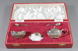 A Georgian style oval silver mustard pot with demi-reeded  decoration and matching salts with blue glass liners and 2 condiment spoons, with Jubilee hallmark, 3 ozs, cased