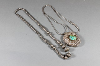 An Eastern white metal pendant set a cabouchon cut green stone  hung on a fine chain and 1 other Eastern white metal chain