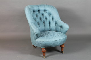 A late Victorian mahogany framed low seat tub chair with blue foliate woven upholstery on turned tapered legs and casters