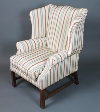 A George III style mahogany framed wing open arm chair having cream, blue and red striped upholstered raised on frog back  moulded square legs united by an H stretcher