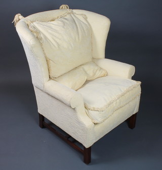 A George III style mahogany framed wing arm chair, floral cut yellow upholstery, raised on moulded square legs united by an H  stretcher