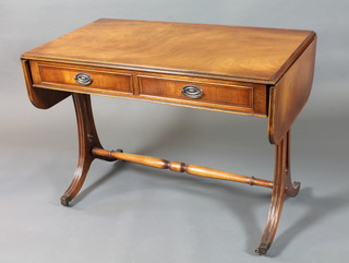 A George III style mahogany sofa table, yew wood crossbanded  fitted 2 frieze drawers, raised on splayed moulded supports united  by a turned stretcher, brass caps and casters 29.5"h x 59.5"w x  22"d