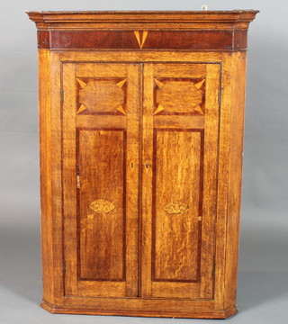 A George III North Country oak hanging corner cupboard, mahogany crossbanded, the 2 cupboard doors enclosing 3 shaped  shelves 43"h x 31"w x 19"d