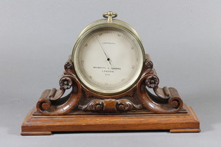 Negretti & Zambra London, a mid 19th Century brass drum cased aneroid barometer, having silvered calibrated dial, raised  on a scroll carved oak mount, plinth base 8"h x 11"w x 3.5"d
