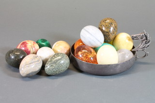 A circular metal dish decorated a horses head and a collection of hardstone eggs