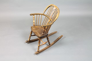An early 20th Century childs high back Windsor rocking chair  with pierced and shaped vase splat, raised on turned legs and  rockers