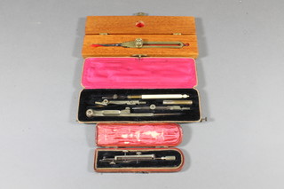 A pair of brass navigational compasses by Elliott Bros. London, cased, a cased geometry set and a cased writing implement set