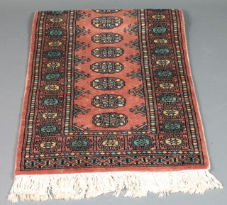 A contemporary pink ground Bokhara runner with 15 octagons to the centre within multi row border 71" x 26"