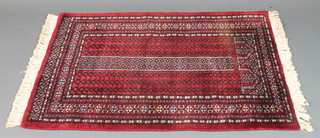 A red ground Bokhara rug with geometric decoration to the centre 45" x 32"