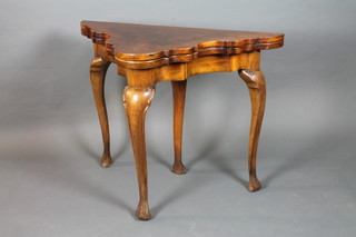 An early 20th Century burr walnut tea table in the Queen Anne  style, crossbanded with hinged top supported by pull out leg,  raised on cabriole legs, scroll feet 30.5"h x 40"w x 21"d