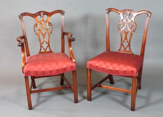 A set of 12 Chippendale style mahogany dining chairs, late 20th Century, two having arms, with foliate carved cresting rails  above scroll carved and pierced vase splats, having red striped  damask upholstery, raised on frog back moulded and chamfered  legs