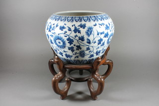 A Chinese circular blue and white jardiniere with floral  decoration raised on a hardwood stand, 13"