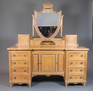 An Edwardian Hepplewhite style pitch pine inverted breakfront dressing chest with shield shaped mirror above 2 cupboards  flanked by a pair of glove drawers, the base fitted a cupboard  flanked by 8 short drawers 67"h x 59"w x 26"w