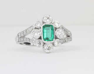 A lady's 18ct white gold dress ring set a rectangular cut emerald supported by diamonds