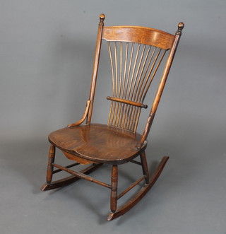 An early 20th Century American oak rocking chair, having  spindle back and saddle seat, raised on ring turned legs and  rockers
