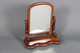 An early Victorian mahogany serpentine toilet mirror having arched top rectangular plate with scroll supports, raised on a  platform base with bun feet 26"h x 21"w x 10"d
