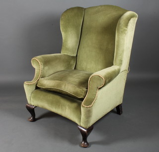 A late 19th Century George II style mahogany framed wing back  arm chair with green velvet upholstery raised on squat cabriole  legs pad feet