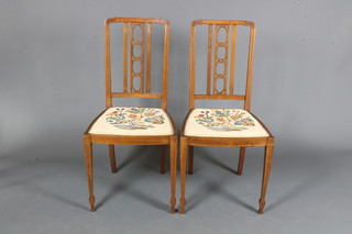 A pair of Edwardian mahogany salon chairs, having pierced interlaced splats above needlework seats, raised on square tapered  legs and shaped feet