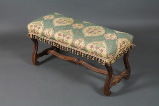 An 18th Century Spanish style walnut window stool having a  foliate tapestry woven stuff-over seat, raised on scrolled legs  united by a shaped and moulded stretcher 18"h x 37"w x 15"d