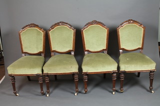 A set of 4 late 19th Century oak dining chairs, the shaped cresting rails carved with bell flowers above a padded back and  stuff-over seat, raised on fluted turned tapered legs and casters  , matching the following lot 152