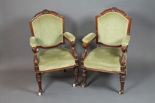 A pair of late 19th Century oak elbow chairs, the shaped cresting  rail carved with bell flowers above a padded back and arms,  stuff-over seat, raised on fluted turned tapered legs ,  matching the chairs in lot 151