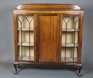 A 1920's mahogany bow front display cabinet having a  gadrooned top above a panelled door flanked by bar glazed doors  enclosing 4 shelves, raised on cabriole legs with claw and ball  feet 50.5"h x 48"w x 14.5"d