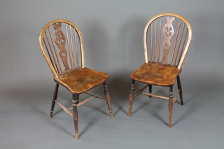 A pair of early 19th Century ash and elm wheel back chairs, having pierced shaped splats above saddle seats, raised on turned  legs