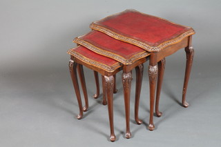 A nest of mahogany tea tables of serpentine form, the tops inset red gilt tooled leather skivers, raised on foliate carved cabriole  legs, pad feet, the largest 23"h x 23"w x 16"d