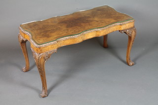 A 1930's walnut serpentine coffee table, crossbanded, the shaped rectangular top foliate carved and supported by cabriole legs and  scroll feet 21"h x 40"w x 20.5"d