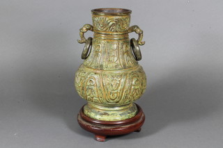 After the Antique a Chinese bronze baluster vase with geometric cast decoration and twin stylised handles on hardwood stand, 9"