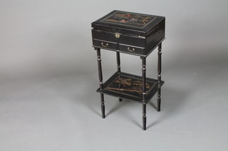 An early 20th Century Japanese black lacquered work box on  stand, the hinged top inlaid with abalone shell and painted with  figures amongst a stylised landscape and enclosing a fitted  interior with 2 short drawers and a second tier below, raised on  turned supports 28"h x 14.5"w x 12"d