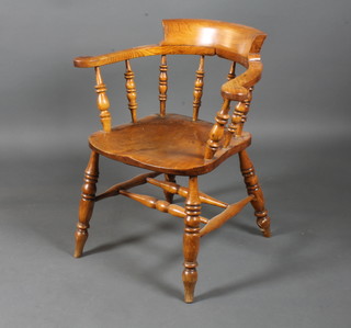 A mid 19th Century oak smoker's bow elbow chair, having horse shoe arms with turned supports, raised on tapered legs united by  a double H stretcher