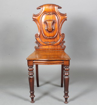 An early Victorian mahogany hall chair having a paper-scroll cresting rail above a shield shaped back with vacant cartouche,  serpentine seat, raised on lappette carved tapered legs  ILLUSTRATED