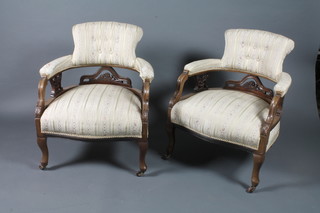 A pair of late Victorian walnut tub back salon chairs upholstered  in striped material, raised on cabriole legs