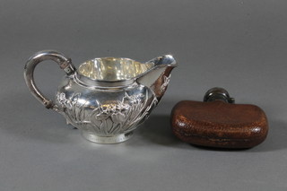 A Chinese Sterling silver cream jug with floral decoration, base marked British Coronation Yacht Race, June 24 1911 and a small  glass and leather hip flask  ILLUSTRATED