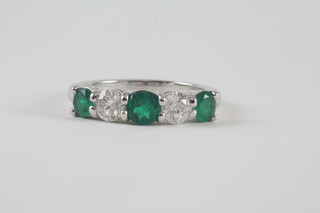 An 18ct white gold dress 5 stone emerald and diamond half hoop eternity ring, emeralds approx 0.81ct, diamonds approx 0.66ct