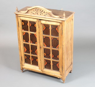 A late 19th Century French stained beech wood wall mounted cabinet, having a pierced cornice above a pair of glazed doors,  decorated transfer stained glass and enclosing 2 shelves 32"h x  23"w x 10"d