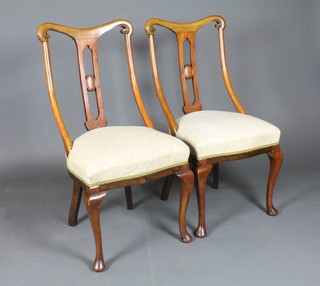 A set of 4 early 20th Century walnut dining chairs, having scroll backs over foliate damask stuff-over seats, cabriole lets