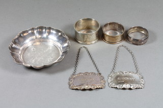 A modern circular silver dish, 3 silver napkin rings and 2 modern decanter labels, 5 ozs