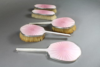 A 5 piece silver and pink enamel backed dressing table set comprising pair of hair brushes, pair of clothes brushes and hand  mirror, Birmingham 1942