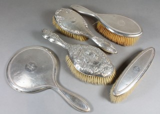 An embossed silver backed hair brush, 1 other hair brush and a 3 piece silver backed dressing table set with hair brush, clothes  brush and handmirror