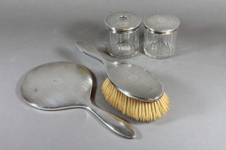 A silver backed handmirror and matching hairbrush, a circular cut glass hair tidy with silver lid, a cylindrical dressing table jar  with silver lid Birmingham 1923