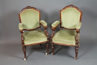 A pair of late 19th Century oak elbow chairs, the shaped cresting  rail carved with bell flowers above a padded back and arms,  stuff-over seat, raised on fluted turned tapered legs
